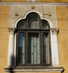 Three-cusped arched Neo-Romanian style house window framed by columns with carved capitals, Bucharest